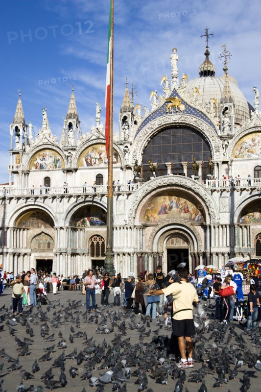 ITALY, Veneto, Venice, Tourists feeding pigeons in Piazza San Marco in front of St Marks Basilica