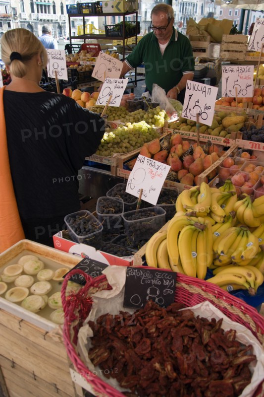 ITALY, Veneto, Venice, Fruit and vegetable stall in the Rialto market with shopper and vendor