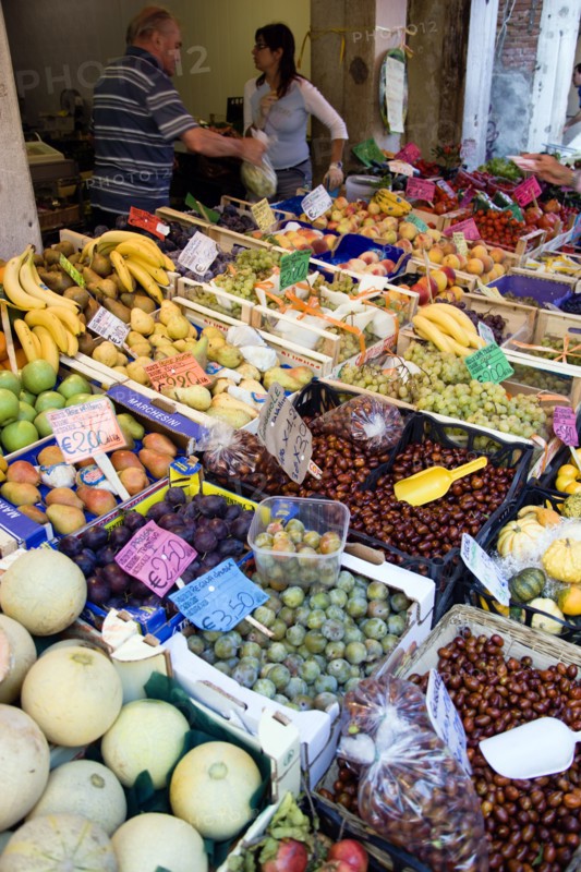 ITALY, Veneto, Venice, Fruit and vegetable stall in the Rialto market with vendors behind the display