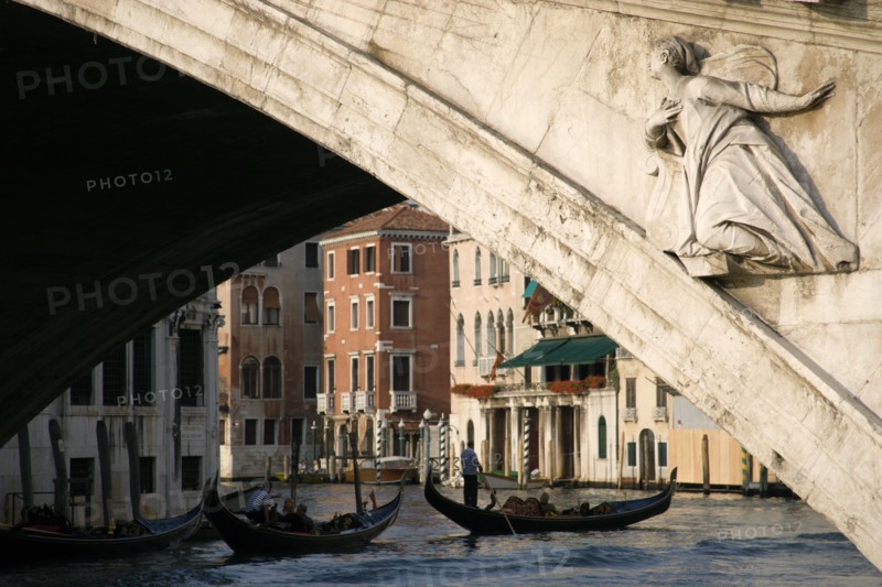 ITALY, Veneto, Venice, A gondola carrying tourists passes beneath the Rialto Bridge over the Grand Canal