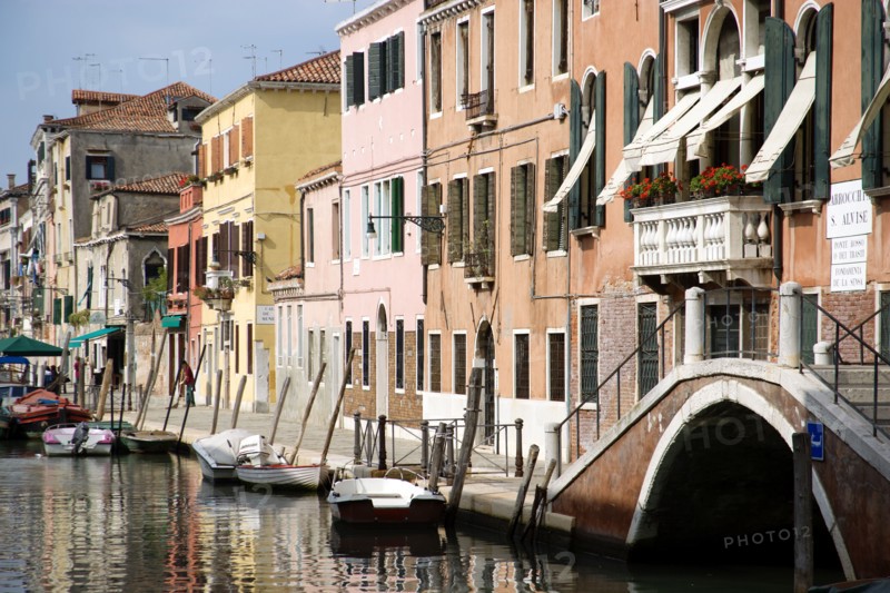 ITALY, Veneto, Venice, Colourful houses along the Fondamenta de la Sensa in Cannaregio district with boats moored along the canal and people walking along the pavement