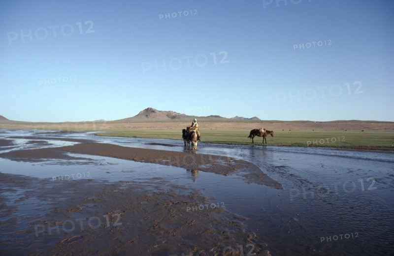 MONGOLIA, Hungui River, Horse back rider wading through shallow river.