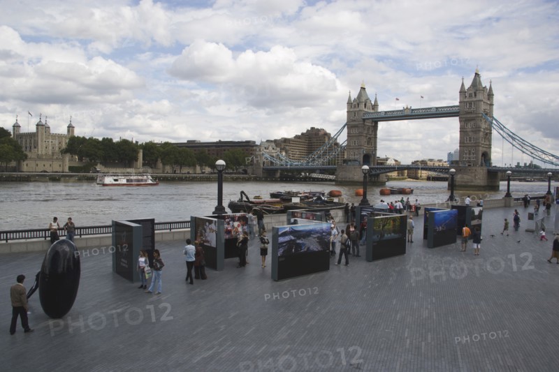 ENGLAND, London, The Queens walk open air exhibition outside the GLA city hall with Tower Bridge behind.