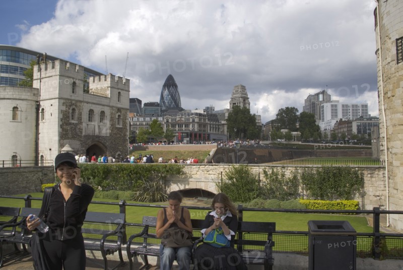 ENGLAND, London, Tourists using their mobile phone outside the Tower of London with the Gherkin Building behind.