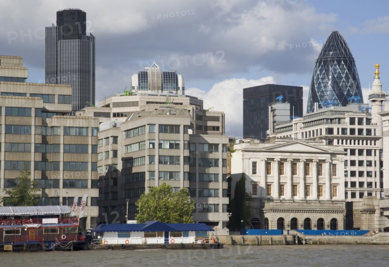 ENGLAND, London, "The Gherkin Swiss Re building seen, through tightly huddled buildings in the city, from London Bridge."