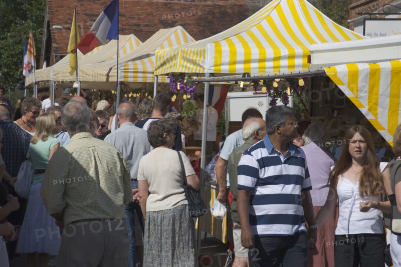 ENGLAND, West Sussex, Shoreham-by-Sea, French Market. People looking around yellow and white striped covered market stalls