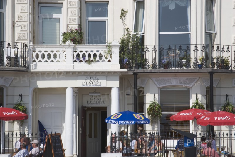 ENGLAND, West Sussex, Worthing, The Last Resort seafront bar exterior with people sitting under parasols drinking