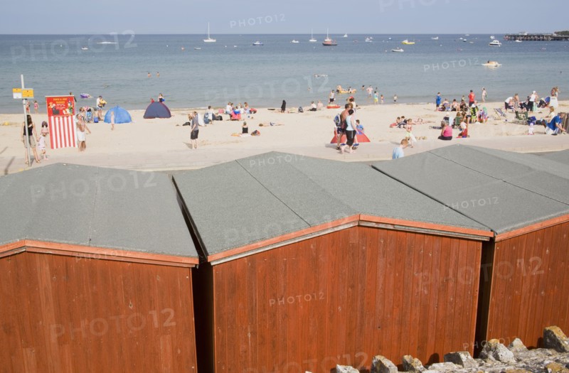 ENGLAND, Dorset, Swanage Bay, View across beach hut roofs towards busy sandy beach and sea
