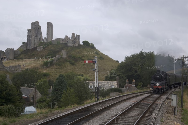ENGLAND, Dorset, Corfe, Corfe Castle seen behind a railway line with a steam train approaching