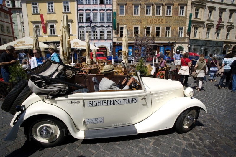 CZECH REPUBLIC, Bohemia, Prague, "Old Town. Vintage open topped car used for sightseeing tours being driven amongst tourists and past a street cafe in Male Namesti, Male Square"