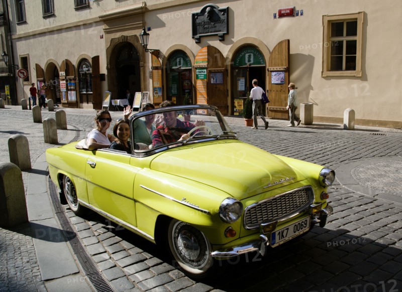 CZECH REPUBLIC, Bohemia, Prague, Tourists in a yellow convertible Skoda used for sightseeing tours around the Old Town