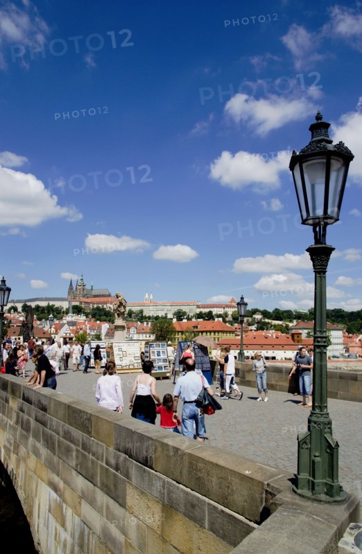 CZECH REPUBLIC, Bohemia, Prague, Tourists on the Charles Bridge across the Vltava River with Prague Castle and St Vitus' Cathedral on the horizon