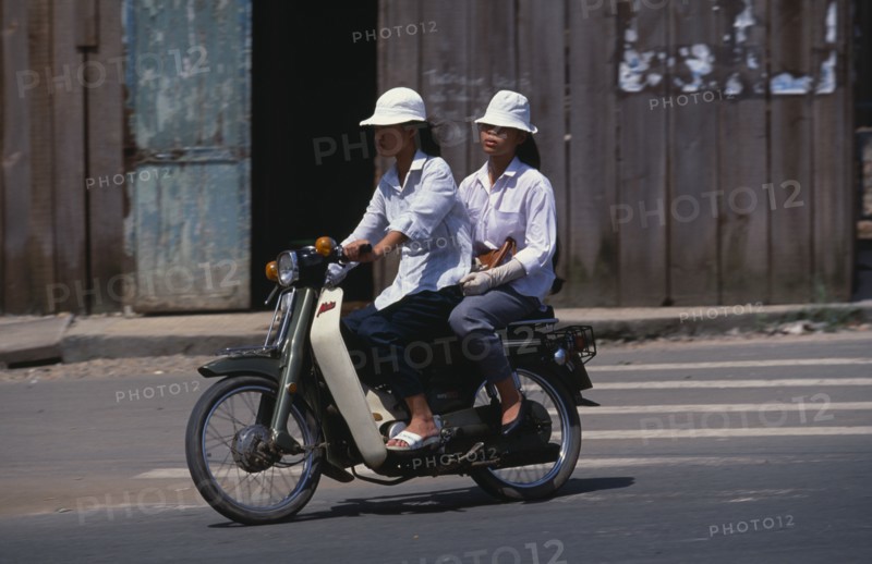 VIETNAM, South, Ho Chi Minh City, Two girls on Honda moped in downtown Ho Chi Minh City.