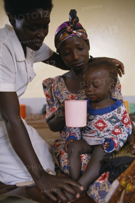 UGANDA, Medical, Nurse comforting mother with child with malaria in hospital in Orukinga refugee camp near the Rwandan border.