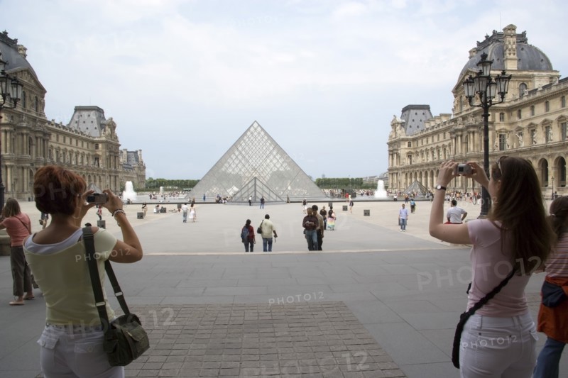 FRANCE, Ile de France, Paris, Tourists taking digital photographs of the pyramid entrance of the Louvre Museum
