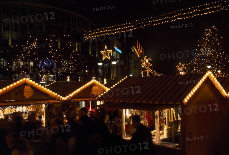 GERMANY, Berlin, Breitscheidplatz. Christmas Market. People gathered around Illuminated stalls at night with lights and star decorations above