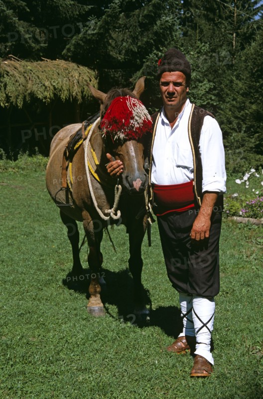 BULGARIA, Chalin Valog, "Man in national costume standing with horse. Pirin Mountain, near Bansko,. "