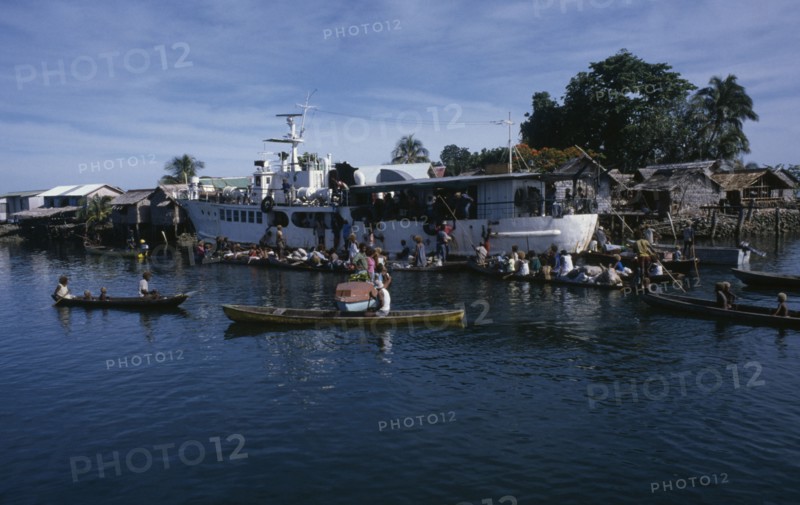 PACIFIC ISLANDS, Melanesia, Solomon Islands, "Malaita Province, Lau Lagoon. Weekly boat service visiting Foueda Island attracting crowds in canoes.  Thatched housing behind.  "