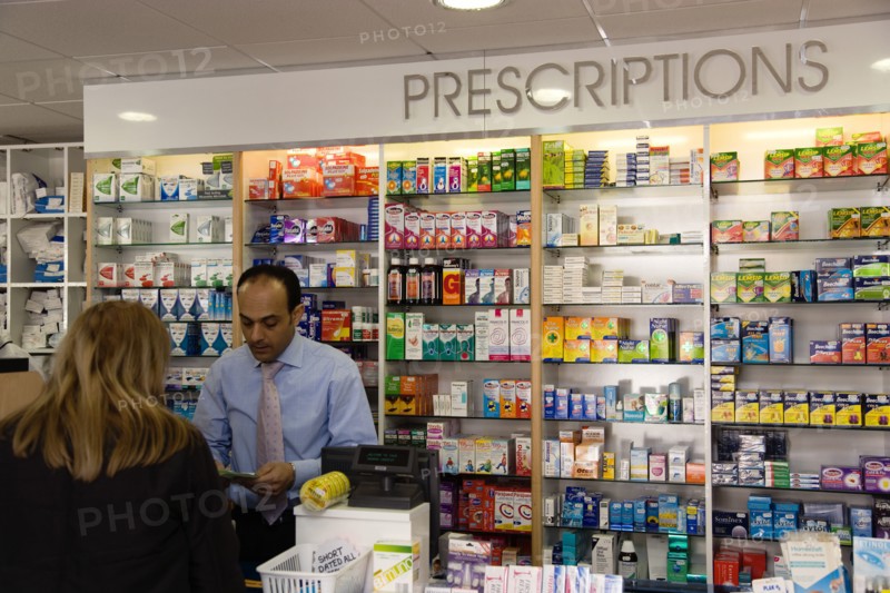 ENGLAND, East Sussex, Shoreham by sea, Interior of high street dispensing chemist  with female customer collecting her prescription from the pharmacist assistant behind the counter