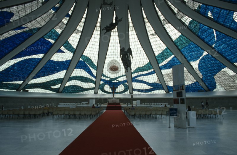 BRAZIL, Brasilia, Cathedral Metropolitana interior with stained glass ceiling and suspended aluminium angels designed by Alfredo Scesciatte.  People on seating in front of altar below.