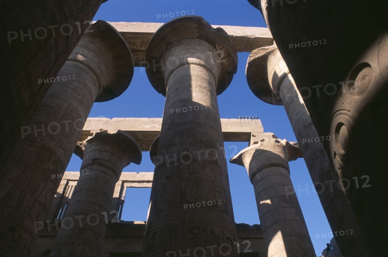 EGYPT, Nile Valley, Karnak, Temple Of Amun. Coloumns in the Great Hypostyle Hall. Angled view looking up through coloumns towards blue sky