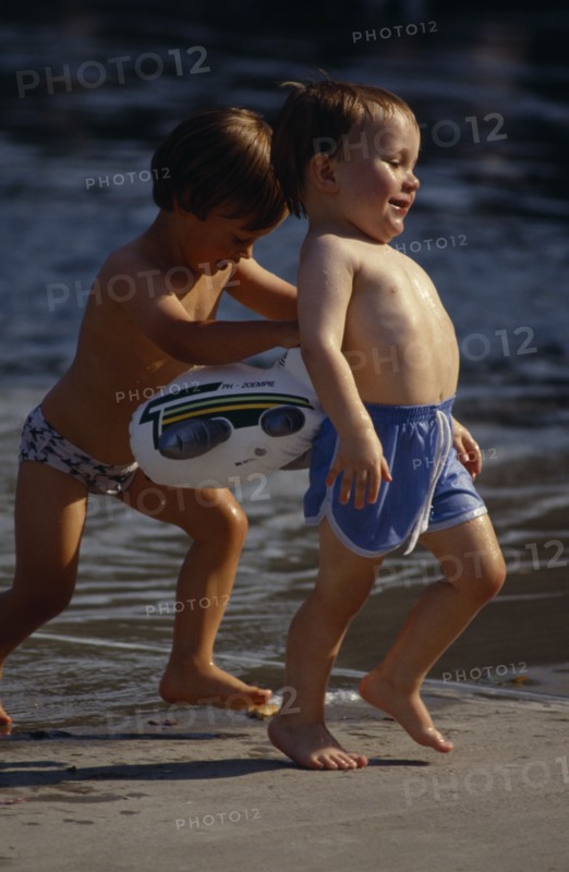 20084756 SPORT Water Paddling Pool Two young boys smiling and laughing playing next to pool with one boy trying to push other into water. Clapham Paddling Pool  London