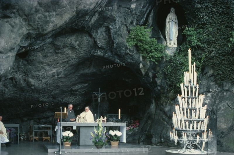 FRANCE, Midi-Pyrenees, Hautes-Pyrenees, Lourdes.  Priest conducting service at cave shrine in pilgrimage centre.