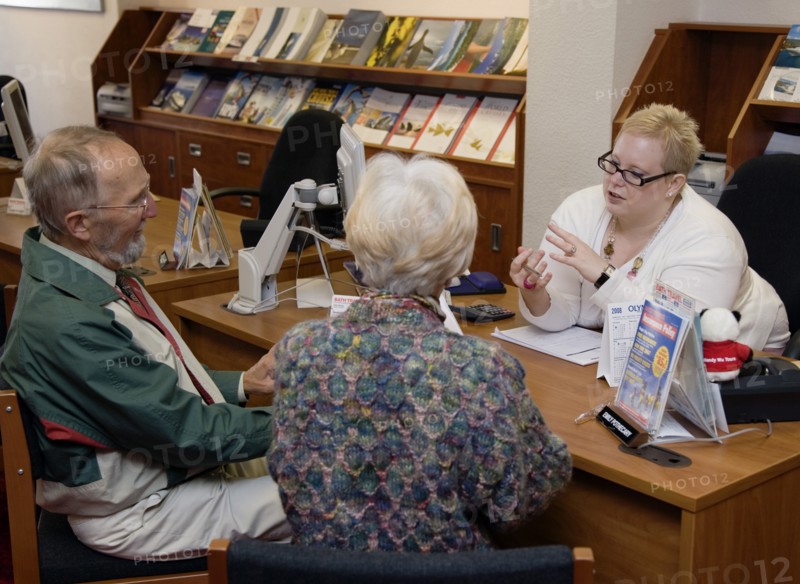 ENGLAND, West Sussex, Chichester, Male and female customer in a Travel Agents office discussing their holiday arrangements with a female travel consultant