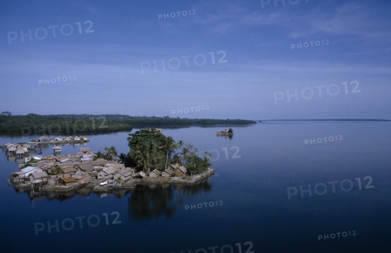 PACIFIC ISLANDS, Melanesia, Solomon Islands, "Malaita Province, Lau Lagoon, Foueda Island.  Artificial man made island and thatched houses, some on stilts with mainland covered by dense forest beyond. "
