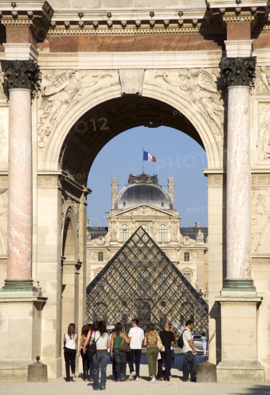 FRANCE, Ile de France, Paris, People walking from the Jardin des Tuileries through the Arc de Triomphe du Carrousel towards the pyramid entrance to the Musee du Louvre
