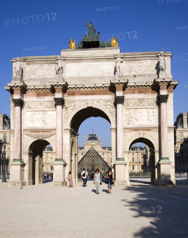 FRANCE, Ile de France, Paris, People walking from the Jardin des Tuileries through the Arc de Triomphe du Carrousel towards the pyramid entrance to the Musee du Louvre