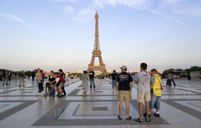 FRANCE, Ile de France, Paris, Young tourists in the main square of the Palais Chaillot at dusk with the Eiffel Tower in the distance
