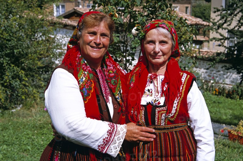 BULGARIA, Dobarsko, "Member of Dobarski Babi Folk Group, and tourist on right, in national costume"