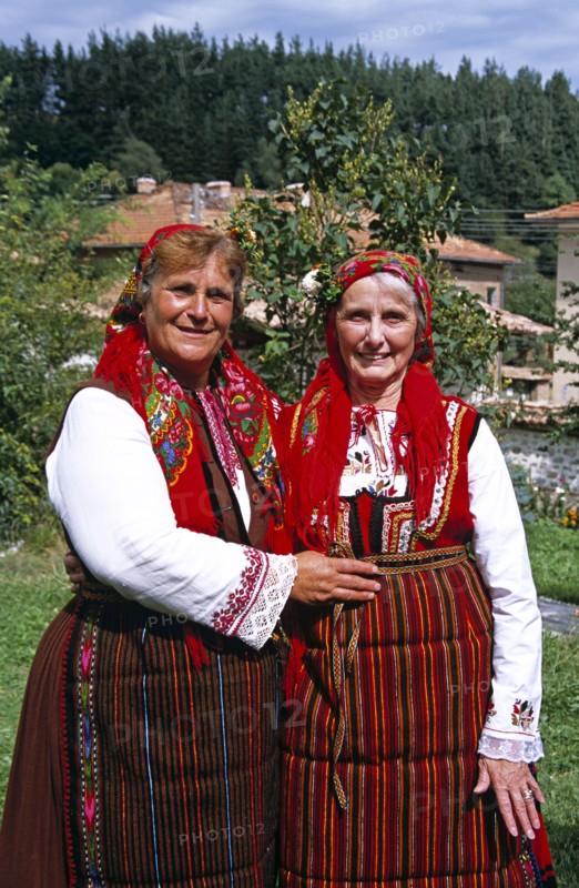 BULGARIA, Dobarsko, "Member of Dobarski Babi Folk Group, and tourist on right, in national costume"