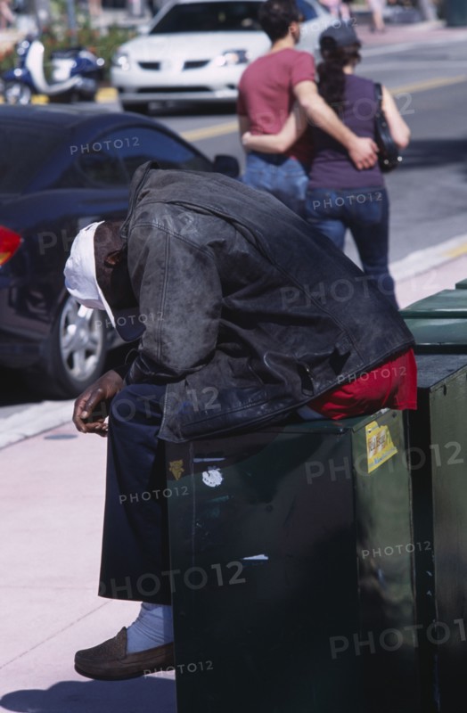 USA, Florida, Miami, South Beach. Ocean Drive. A Homeless man sitting on a news stand asleep