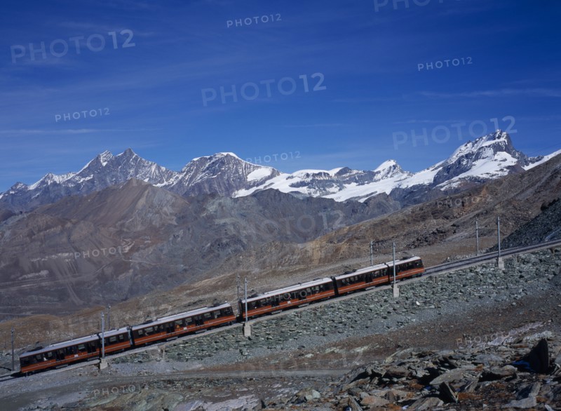 SWITZERLAND, Valais, Zermatt, "Gornegrat Railway with train traveling past snow capped mountains left to right, Oberrothorn 3414metres   ( 11180ft  ) and Fluehorn 3317metres ( 10863ft )"