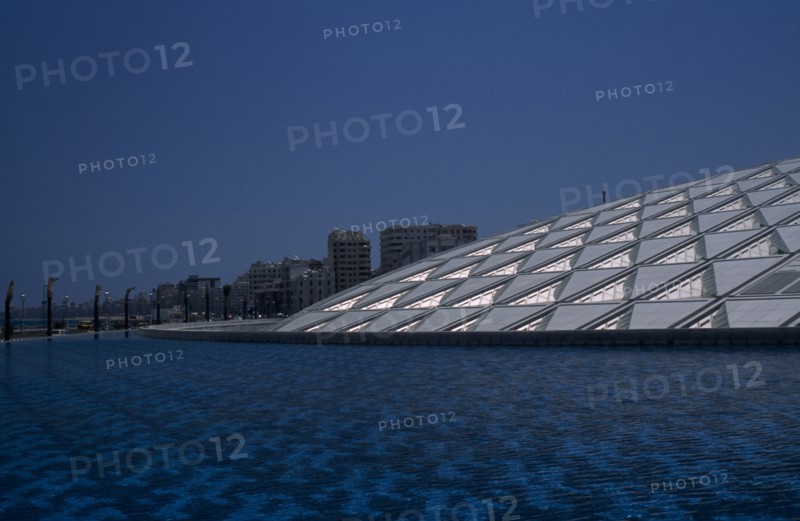 EGYPT, Nile Delta, Alexandria, Bibliotheca Alexandrina modern library exterior with detail of interlocking panelled roof seen from across pool of water