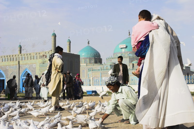 AFGHANISTAN, Mazar-I-Sharif, "Family feeding famous white pigeons at Shrine of Hazrat Ali (who was assissinated in 661) This shrine was built here in 1136 on the orders of Seljuk Sultan Sanjar, destroyed by Genghis Khan and rebuilt by Timurid Sultan Husain Baiqara in 1481, since restored. The shrine is famous for its white pigeons, it is said the site is so holy that if a grey pigeon flies here it will turn white within 40 days"