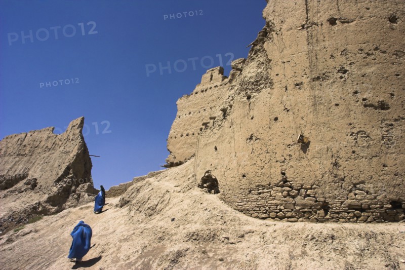 AFGHANISTAN, Ghazni, Ladies wearing burqua walk near ancient walls of Citadel destroyed during First Anglo Afghan war since rebuilt still used as a military garrison Jane Sweeney