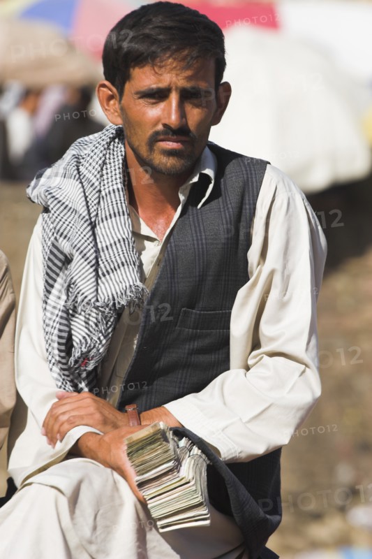 AFGHANISTAN, Kabul, Money changer sits on rug on walls of Kabul river