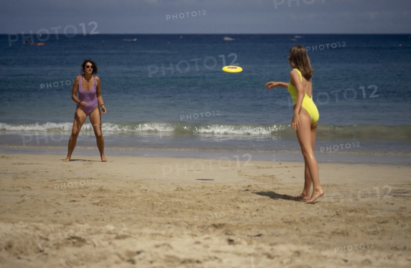 20085230 SPORT Games Frisbee Two women wearing bathing costumes playing Frisbee on sandy beach next to the sea in St Ives  Cornwall  England