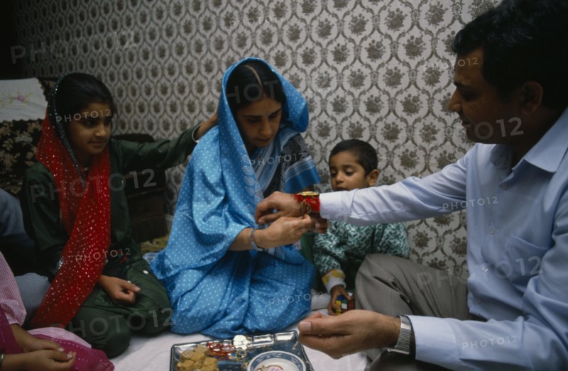 ENGLAND, Religion, Hindu, Woman tying thread on wrist of man during the Sacred Thread ceremony. The Hindu male rite of passage ceremony