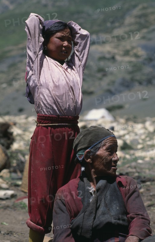 NEPAL, Mustang, Nomads, "Tibetan nomads.  Elderly seated woman with young girl standing behind with arms raised behind head, both looking away to right."