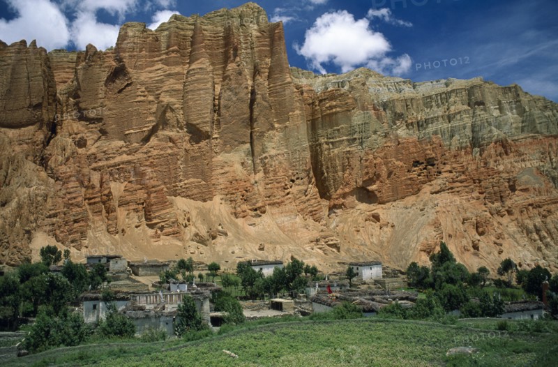 NEPAL, Mustang, Drakhmar, "Summer landscape.  Adobe village housing and cultivated land at foot of steep, eroded cliff.  "