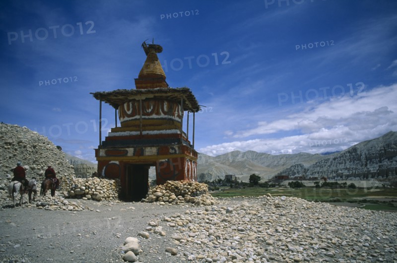 NEPAL, Mustang, Tsarang, "Old, painted stupa marking entrance to Tsarang with two horsemen approaching."