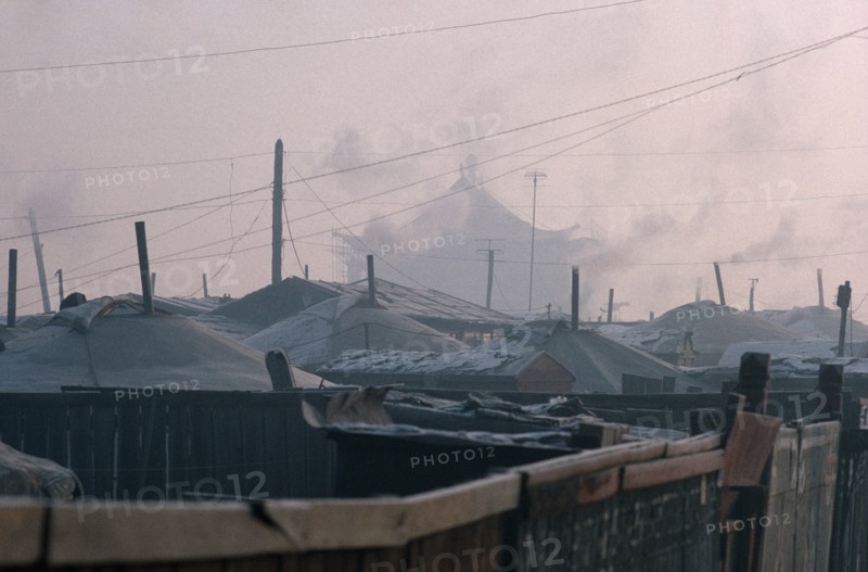 MONGOLIA, Ulan Bator, Yurt district with shadowy grey rooftop of the Gandan Monastery behind in winter.