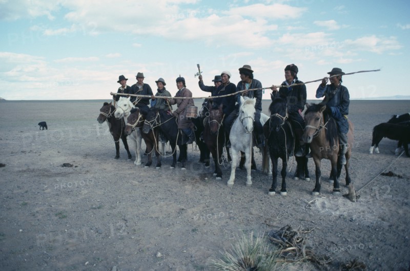 MONGOLIA, South Gobi, Festival, Young herdsmen circling camp abreast on horseback for ceremony of libation of first mare’s milk of the season.
