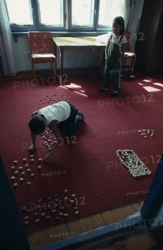 MONGOLIA, Children, Children playing indoors with sheep knuckle bones used to represent herds and pens.
