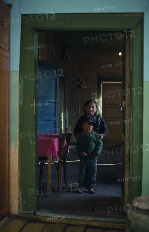MONGOLIA, North, Children, Brother and sister standing in open doorway of home with green painted door frame.