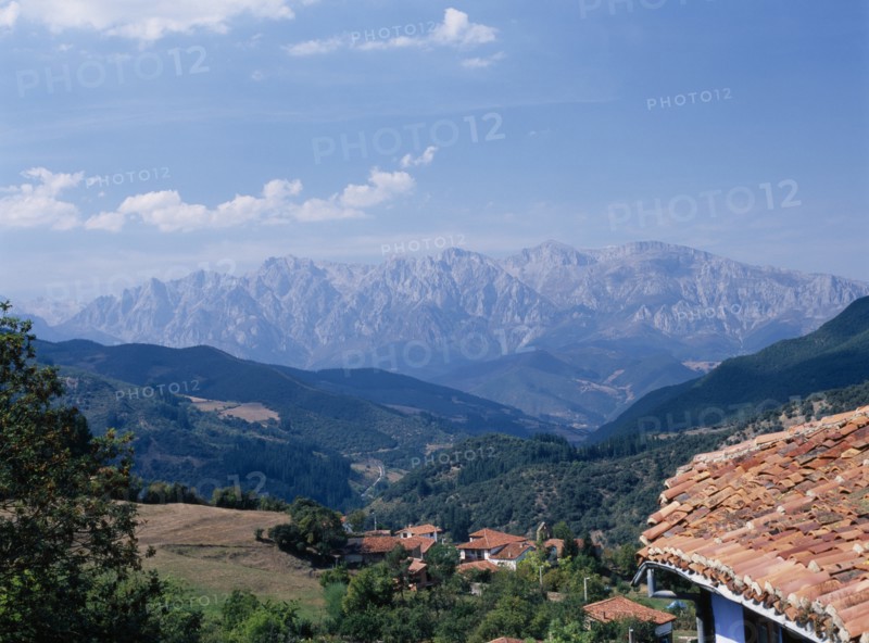 SPAIN, Cantabria, Cabezon de Liebana, "View towards the Picos de Europa mountains in northern Spain from the Posada la Trebede, Perrozo. Tiled rooftops of village and the Val de Liebana valley."